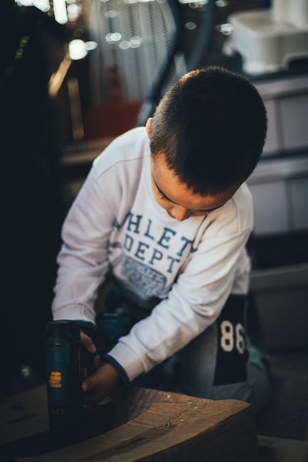 A cluttered workbench situated in a garage workshop with a turquoise painted wall behind it. The workbench surface is made of wood and is covered with various tools, including pliers, screwdrivers, an